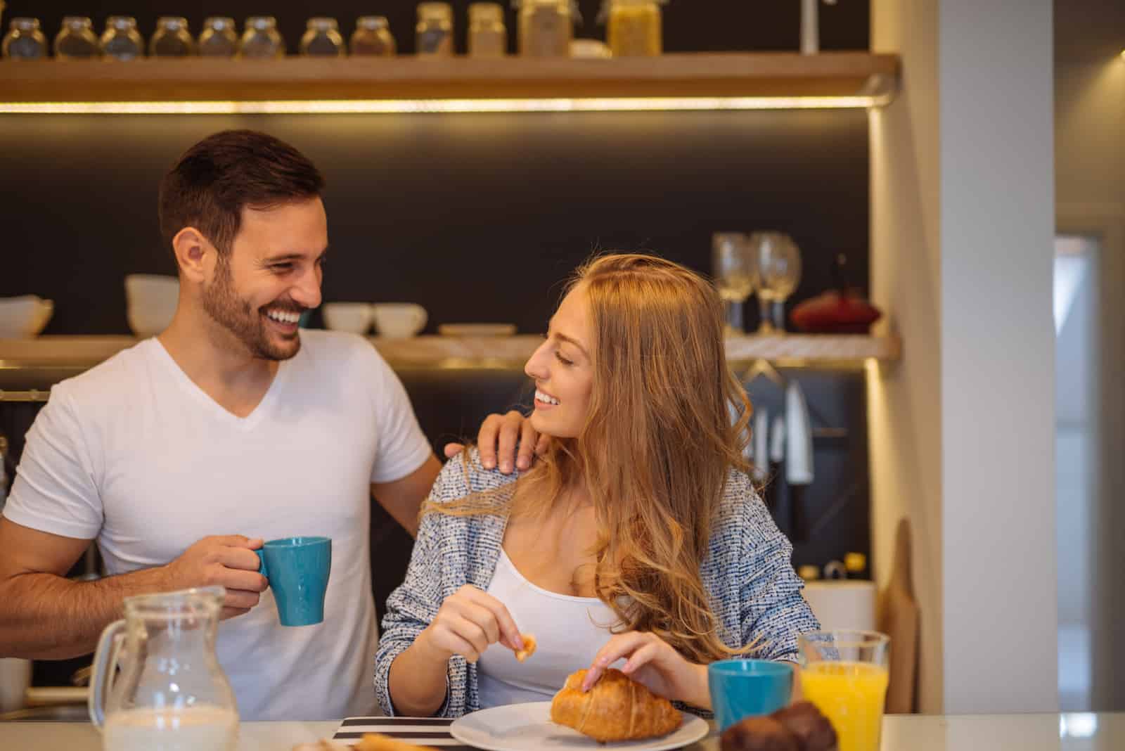 couple souriant parlant tout en prenant son petit déjeuner dans la cuisine