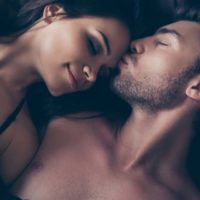 un homme embrasse une femme sur le front en position couchée dans son lit