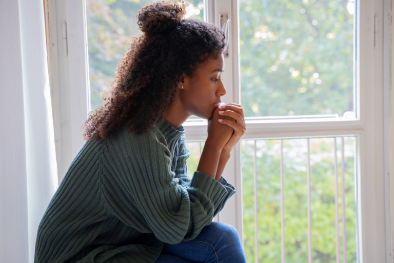 une femme est assise sur un canapé et prie