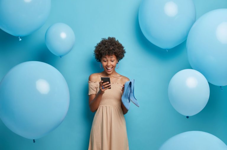 femme ravie lisant un message texte avec des ballons autour