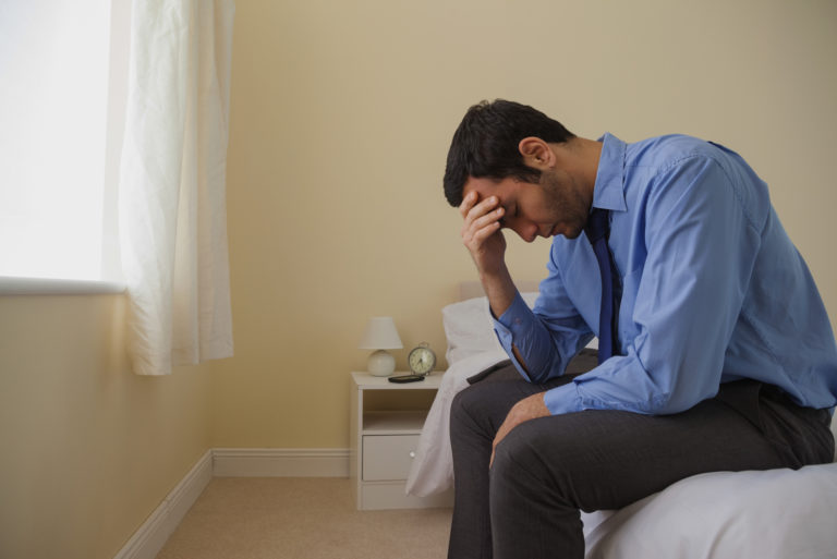homme assis sur son lit et pleurant