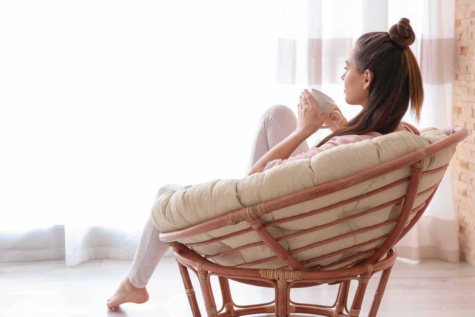 femme assise sur une chaise regardant par la fenêtre