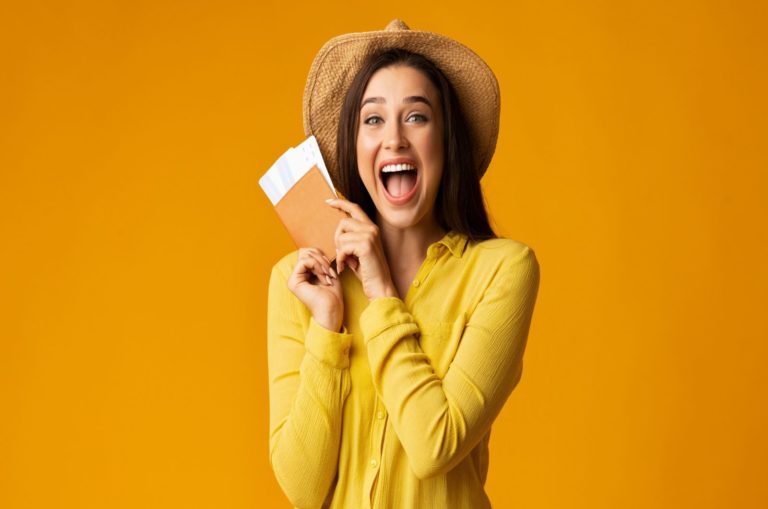 Fille tenant des billets et passeport sur fond jaune