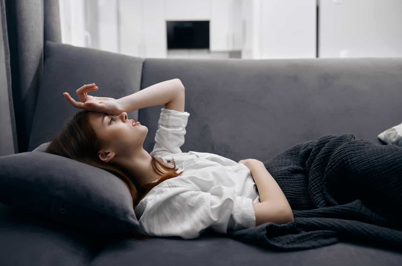 femme allongée sur un canapé ayant mal à la tête