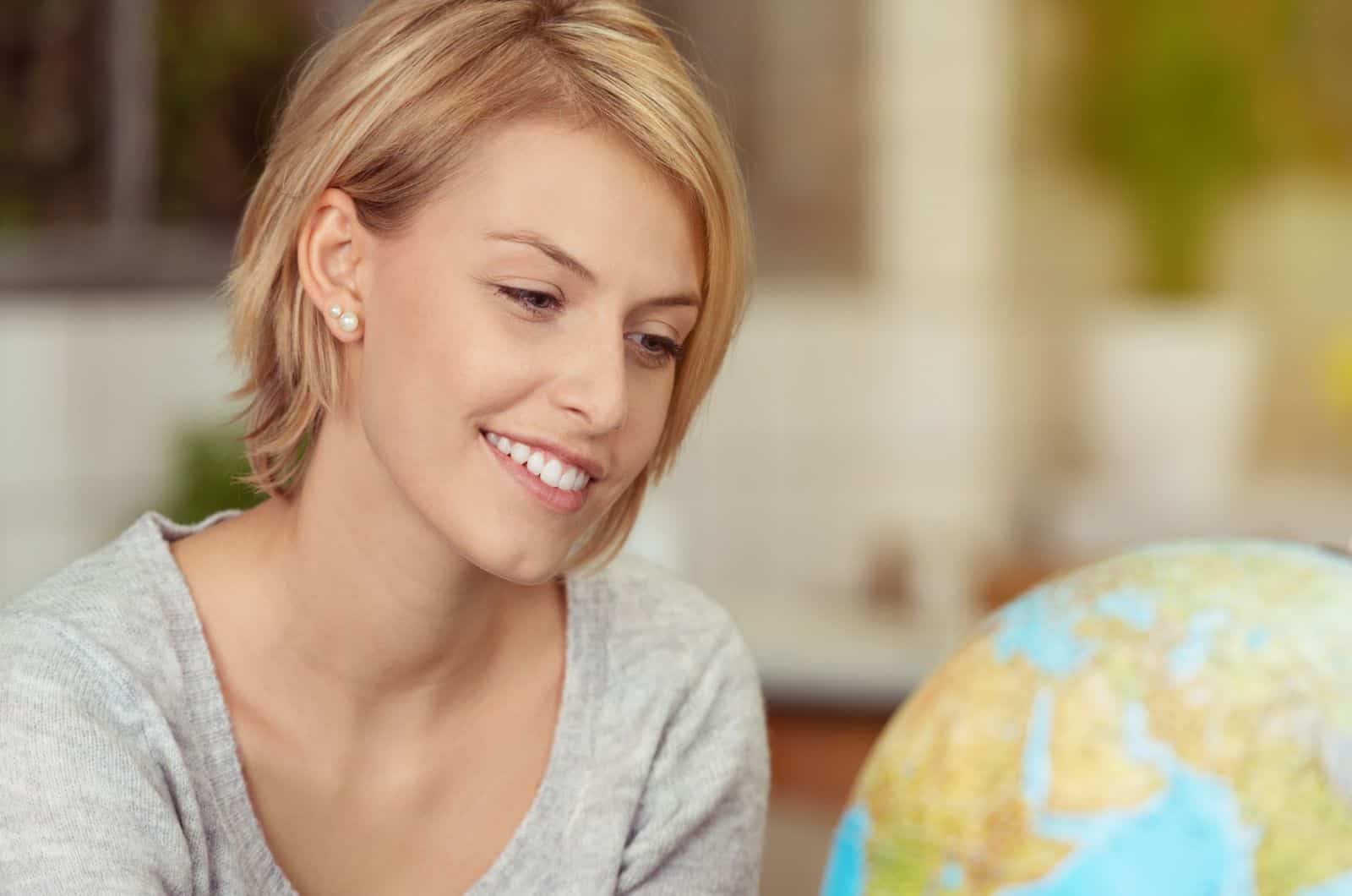 femme souriante regardant le monde globus