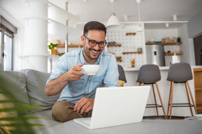 homme souriant assis devant un ordinateur portable