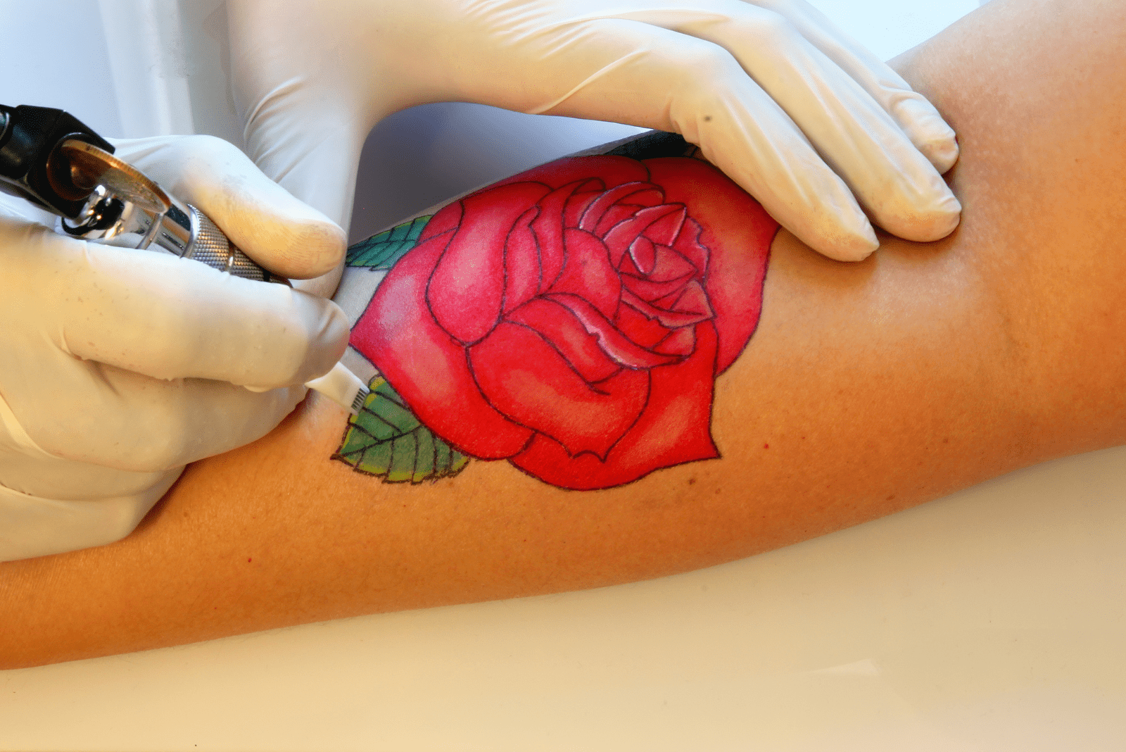 un homme se tatoue une rose rouge sur le bras