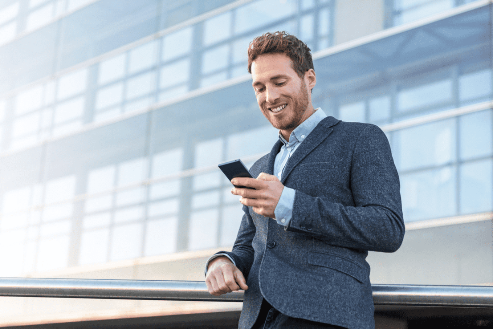 un homme souriant est debout et tient un téléphone portable dans sa main