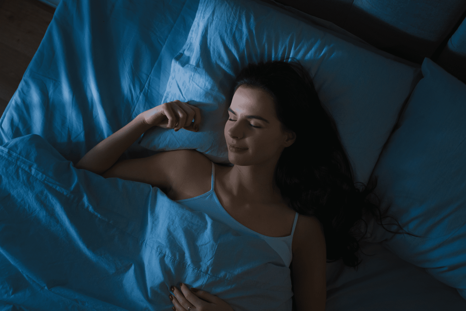 une femme aux longs cheveux bruns dort dans son lit