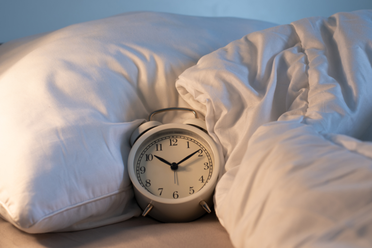 une horloge blanche sur la couette dans le lit