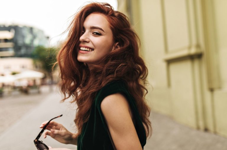 jolie femme en tenue vert foncé souriant à l'extérieur