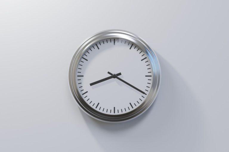Horloge chromée brillante sur un mur blanc à huit heures vingt