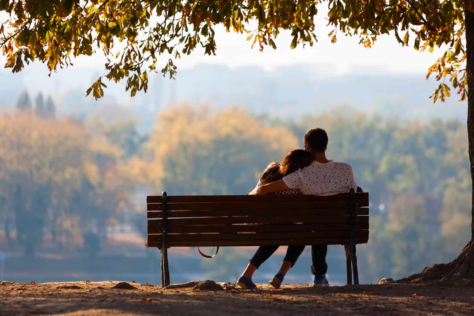 homme tenant une femme assise sur un banc à l'extérieur