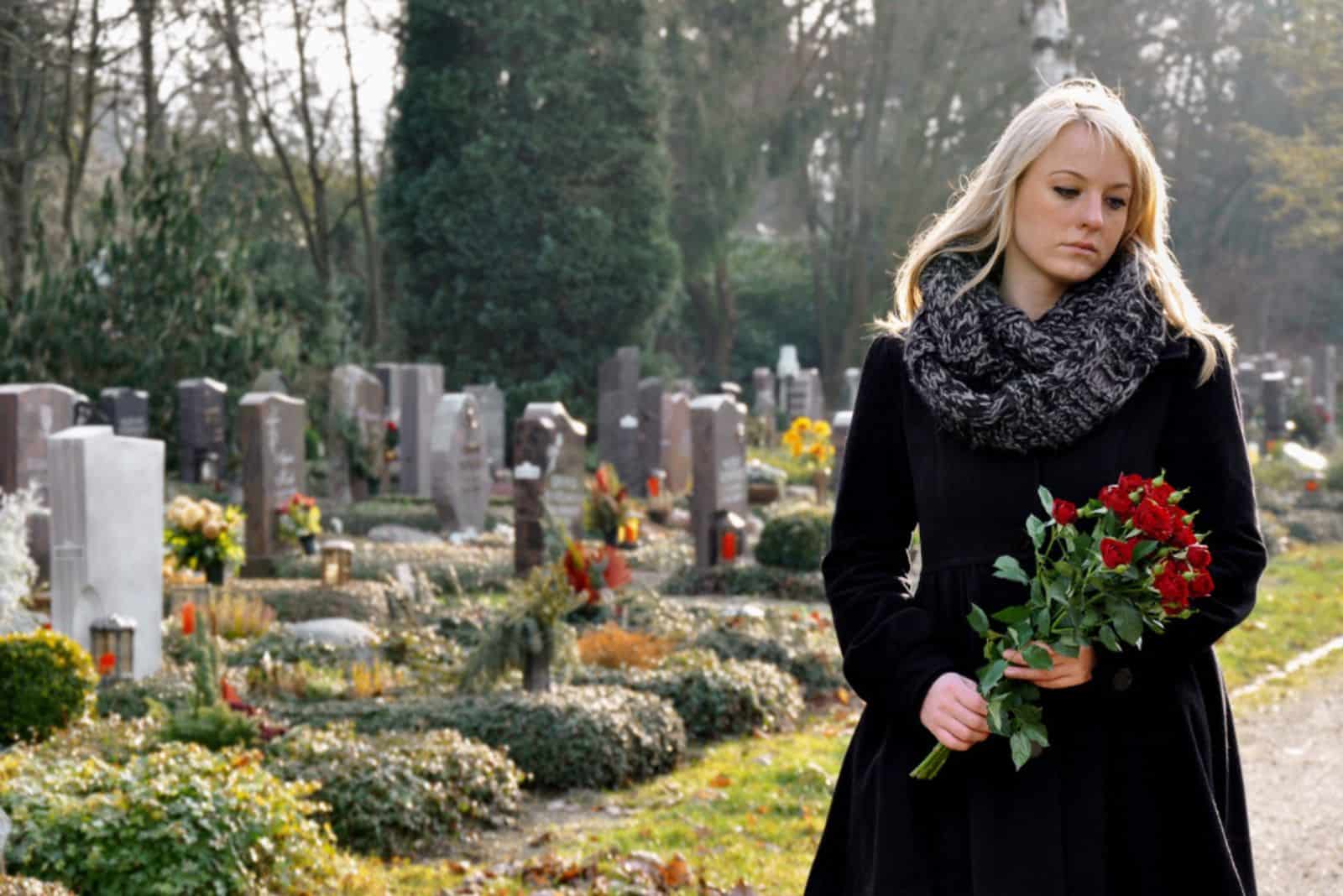 Femme au cimetière avec un bouquet de roses