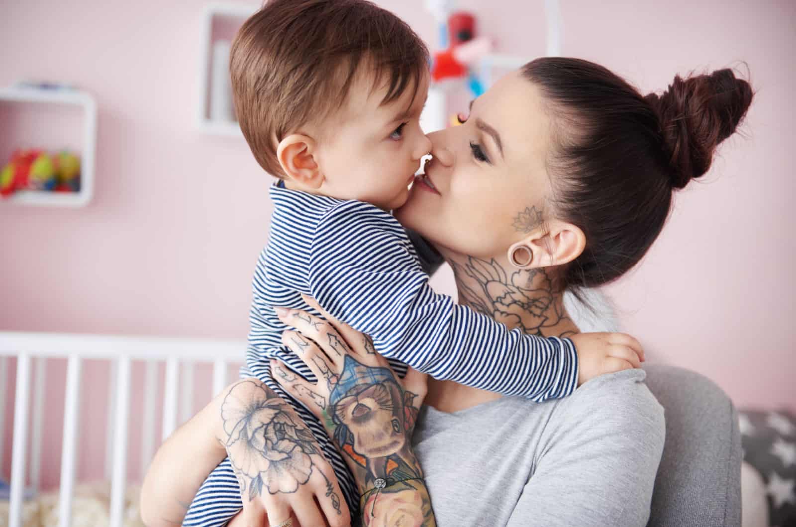 femme tatouée tenant son enfant