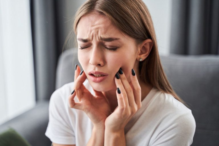 Fille souffrant de douleurs dentaires et touchant la joue