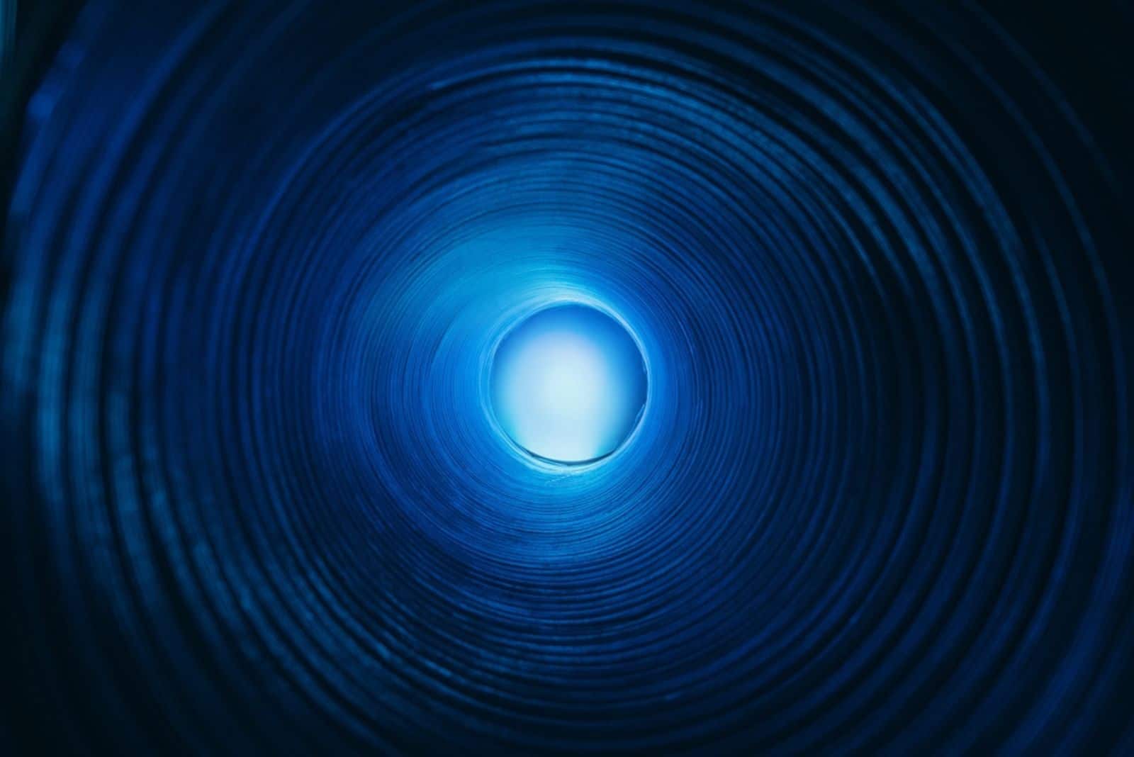 Sphère de lumière lunaire de couleur bleu néon défocalisé dans un tunnel de texture de tourbillon strié