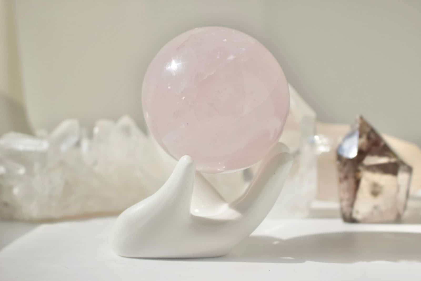 Sphère de quartz rose sur la main en porcelaine blanche