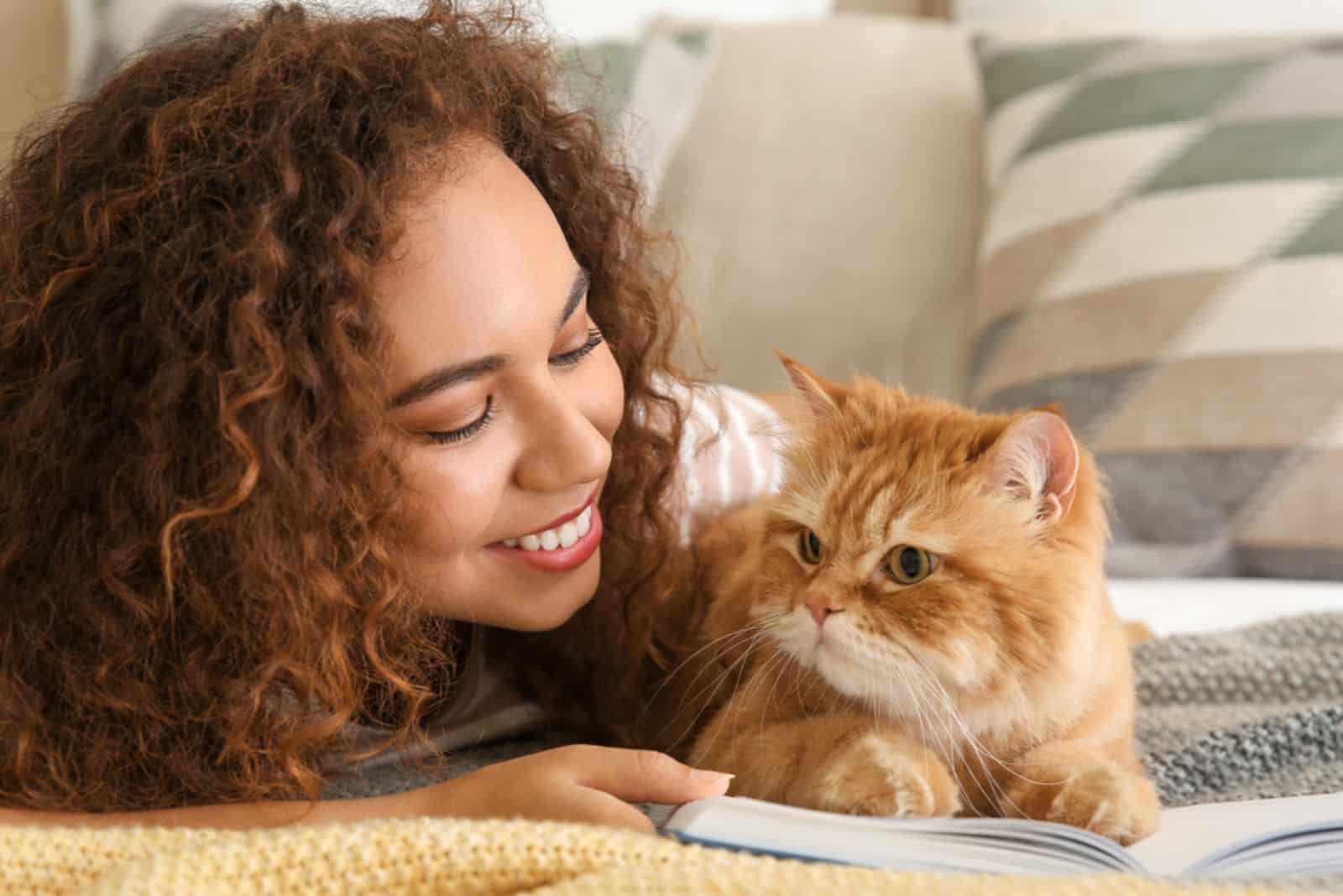 femme avec un chat mignon lisant un livre à la maison