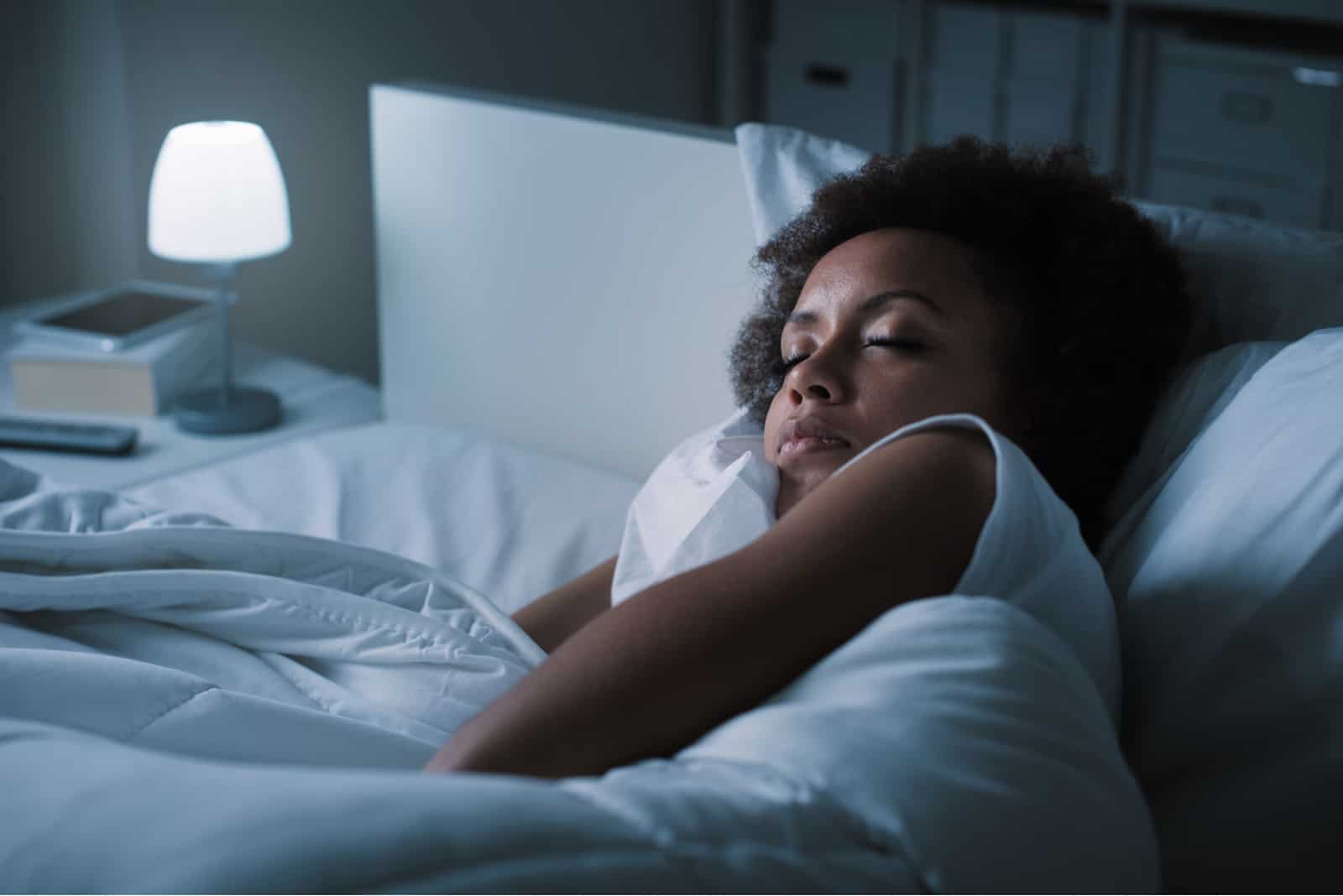 femme dormant dans son lit avec des draps blancs