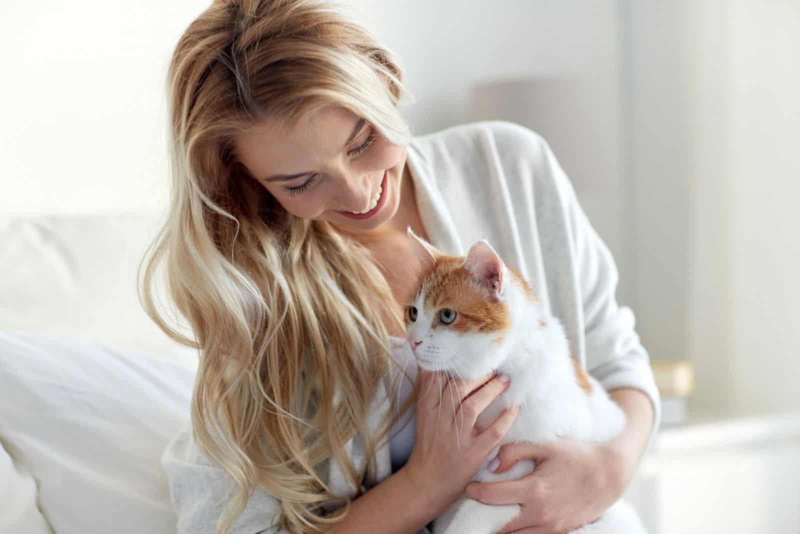 heureuse jeune femme avec un chat au lit à la maison