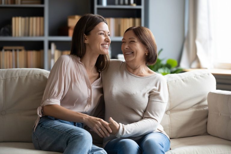 deux femmes souriantes sont assises sur le canapé