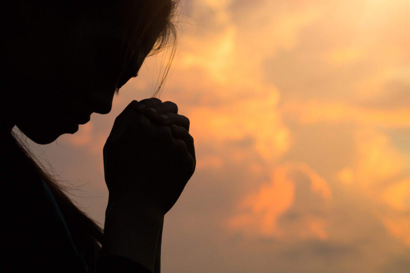 Silhouette de mains de femme priant Dieu avec la bible