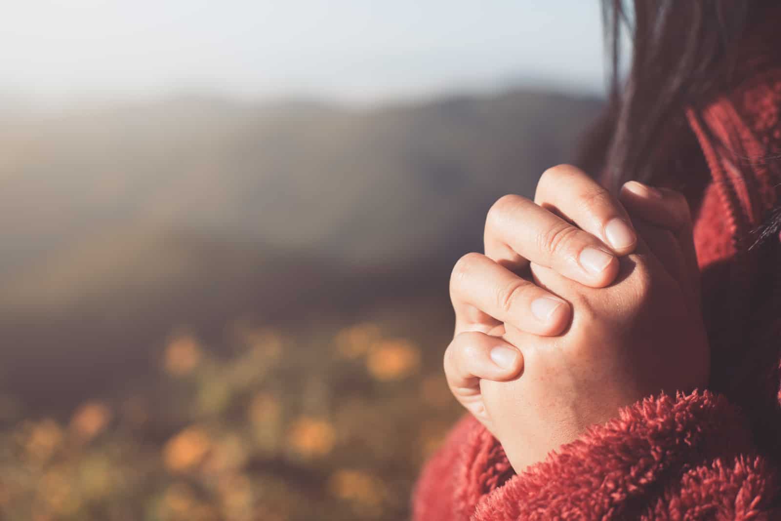 Mains de femme jointes en prière dans la belle nature