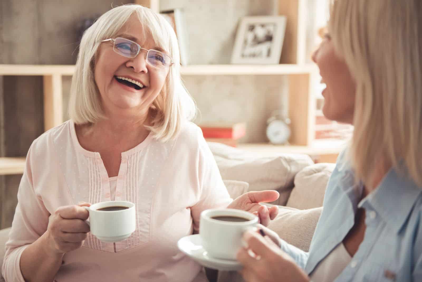 deux femmes sont assises sur le canapé avec du café et parlent