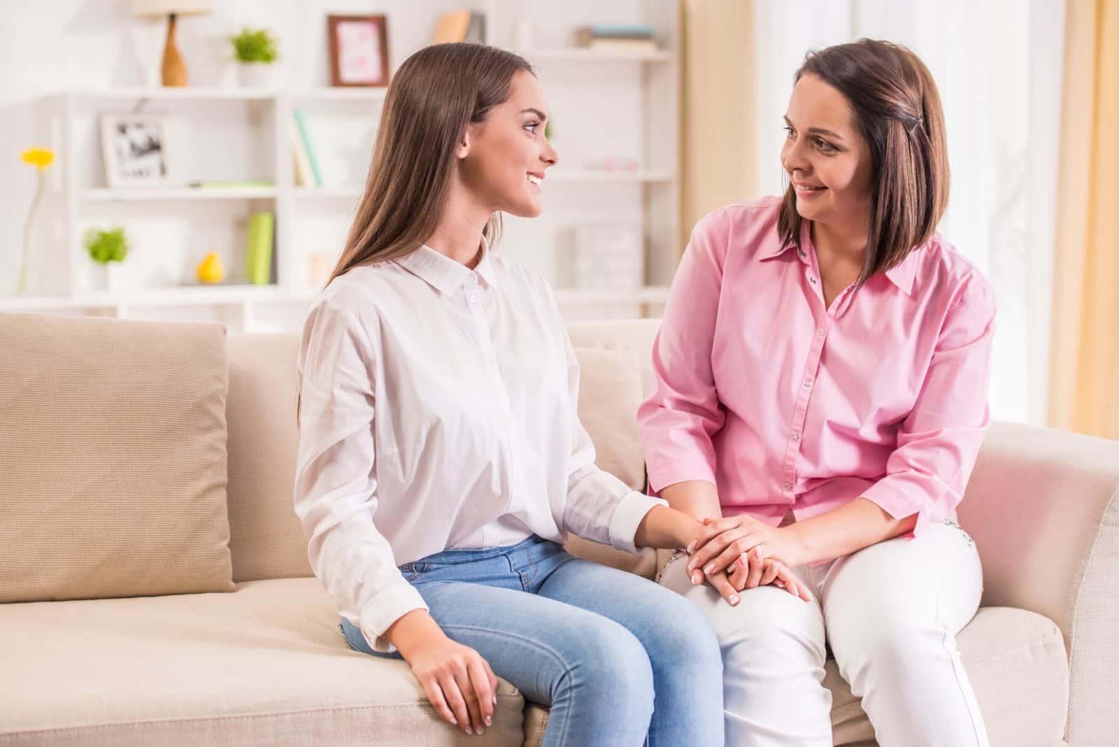 deux femmes souriantes sont assises sur le canapé et parlent