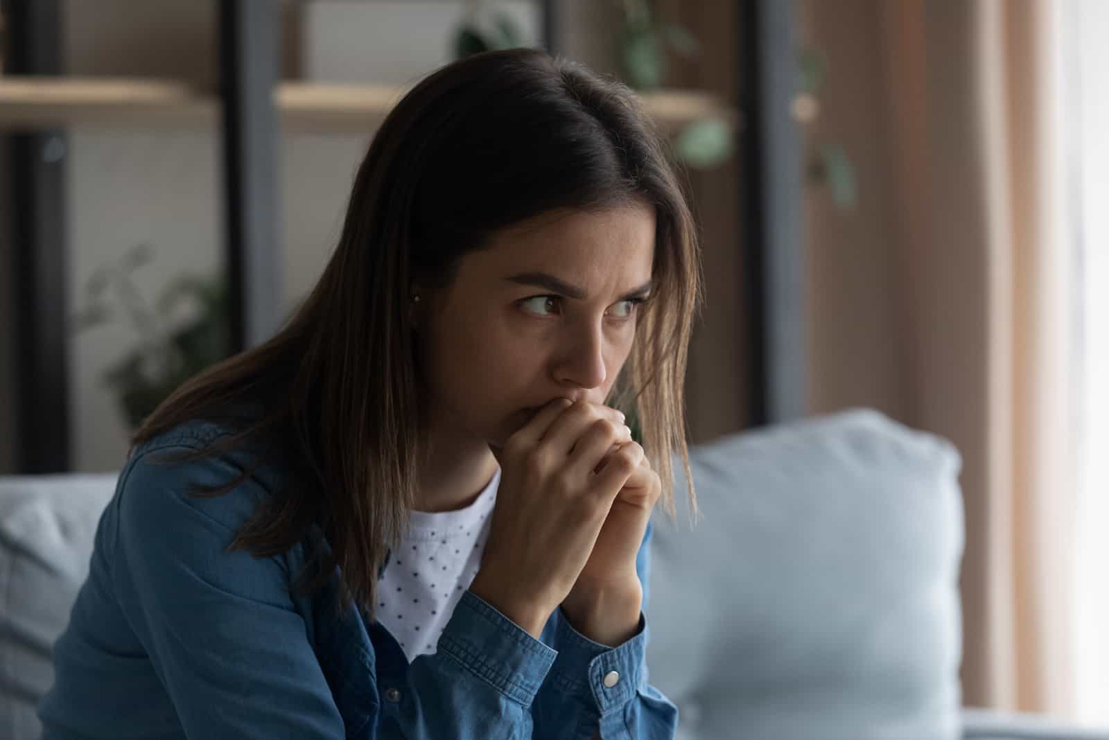 femme inquiète assise sur un canapé en détournant les yeux