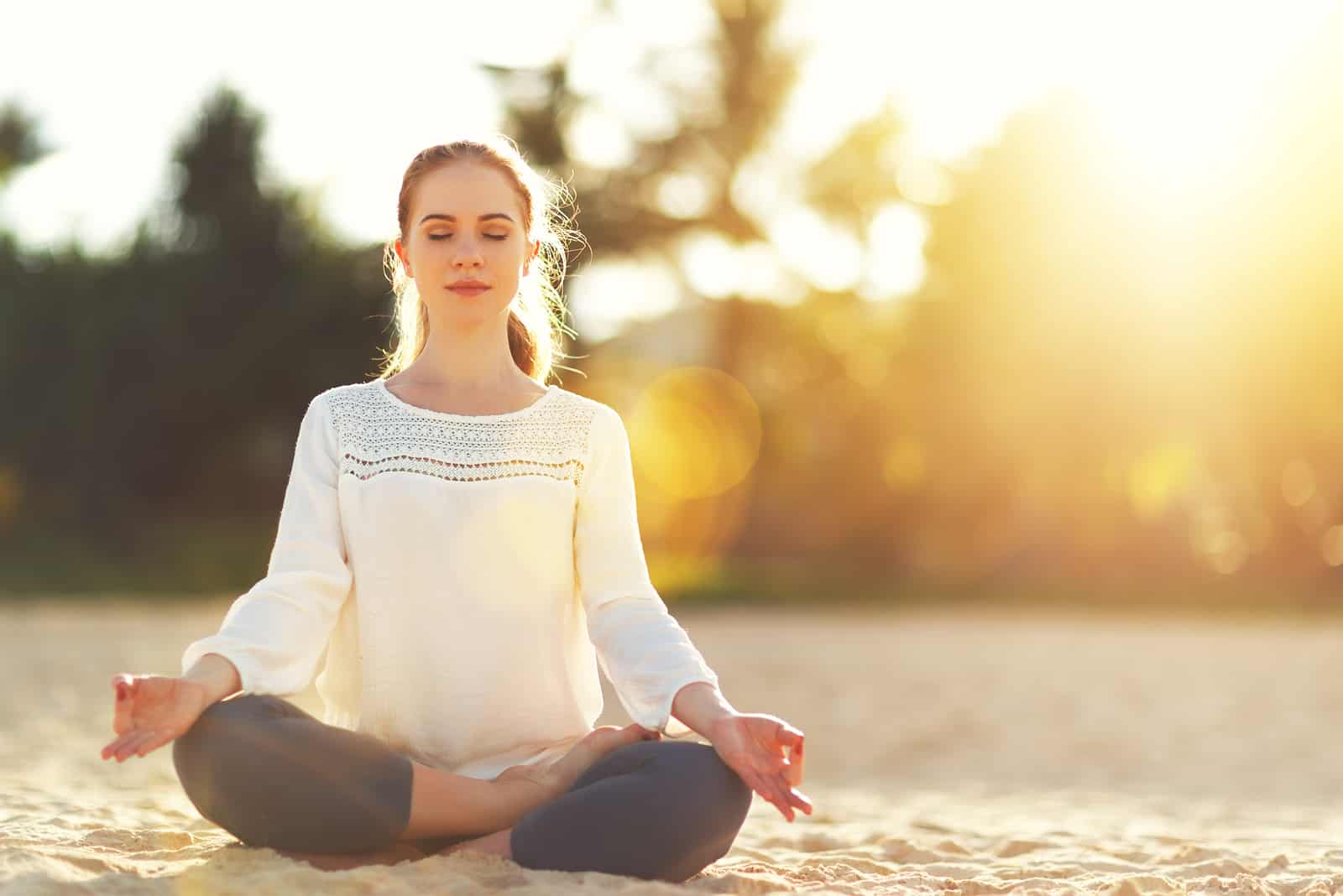 femme pratiquant le yoga et la méditation en position du lotus sur la plage