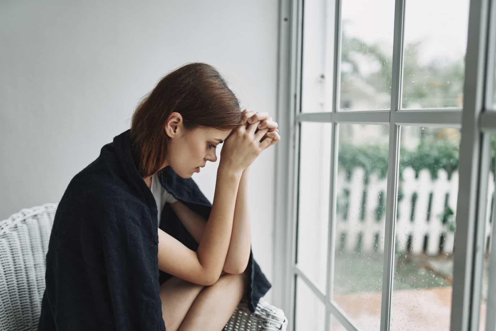 femme triste assise à côté de la fenêtre