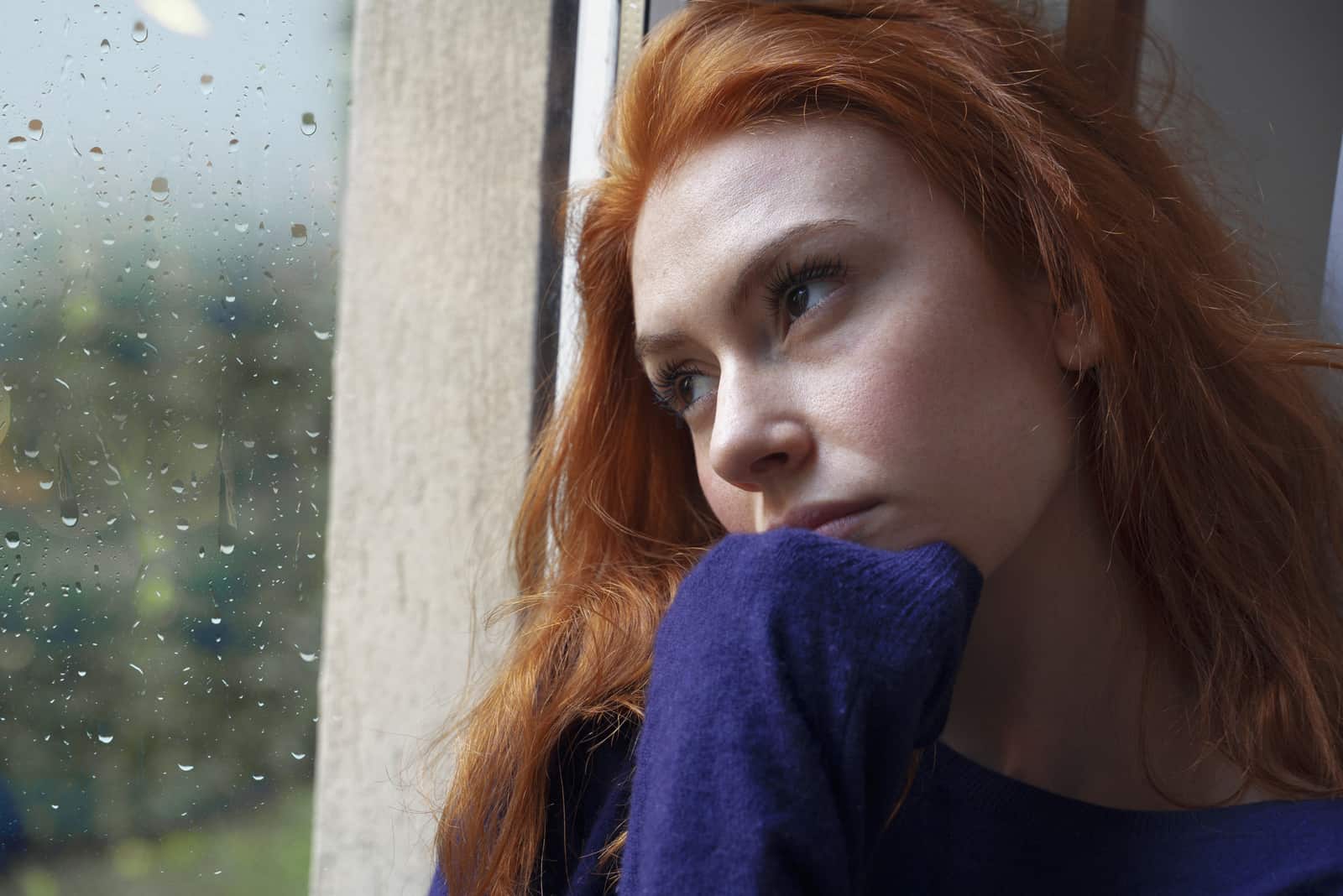 femme triste regardant par la fenêtre