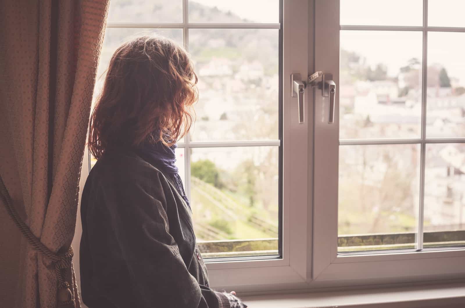 jeune femme regardant par la fenêtre