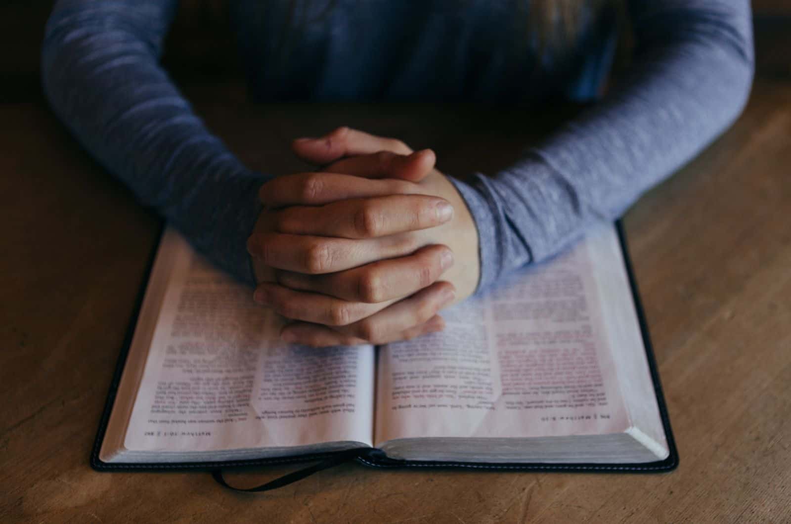 personne priant avec la bible ouverte