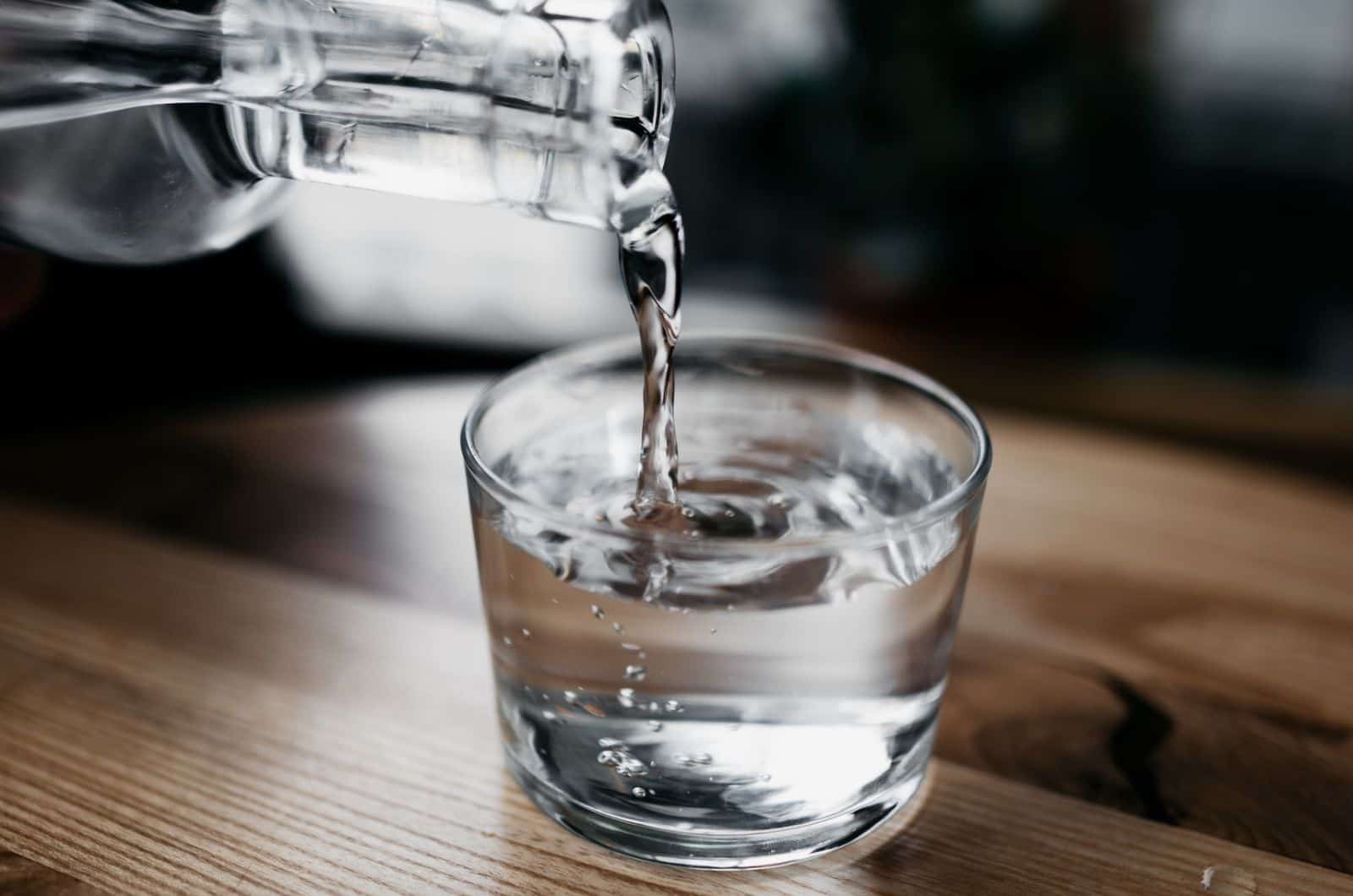 personne versant de l'eau dans un verre