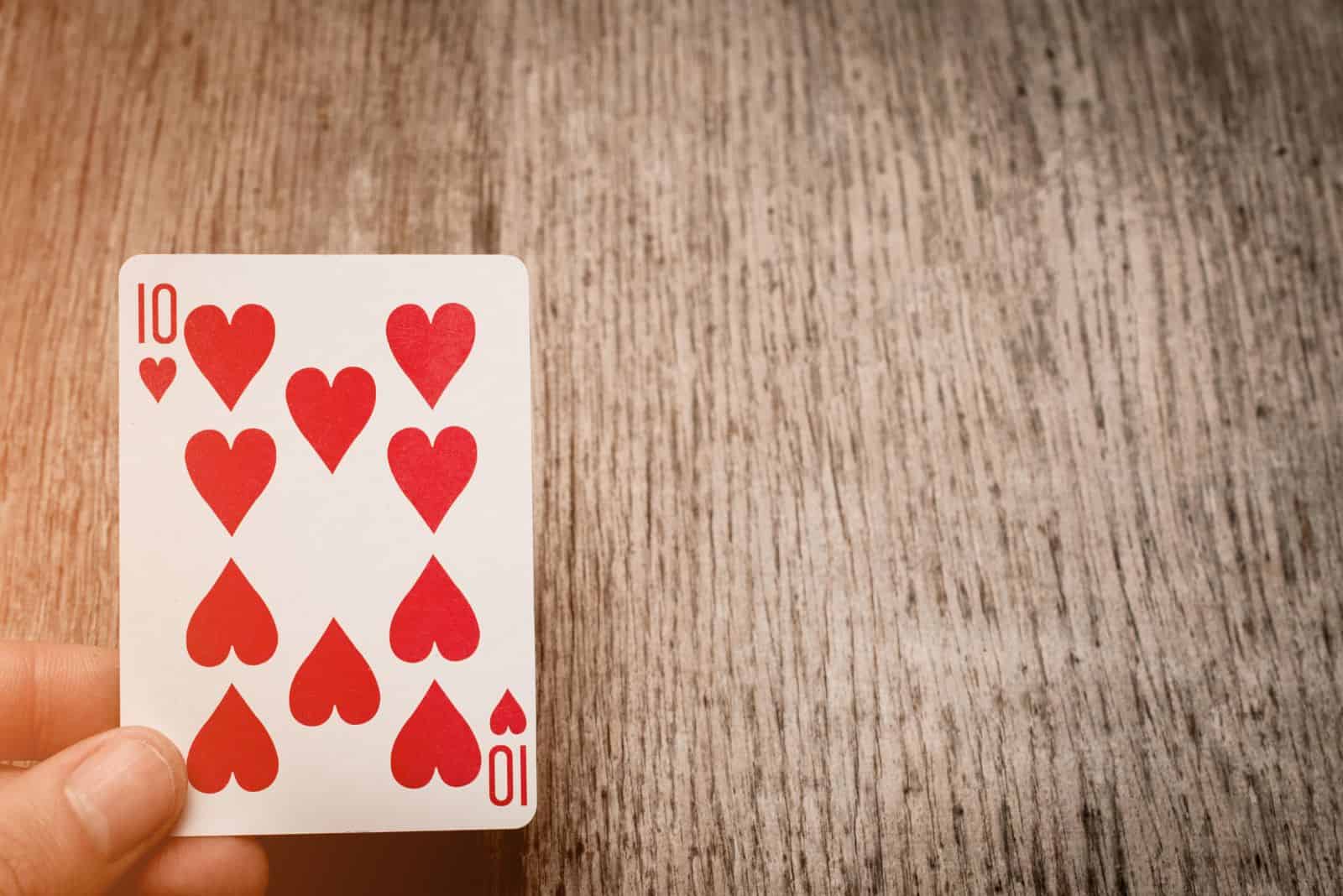 un homme tient un coeur de dix cartes dans sa main