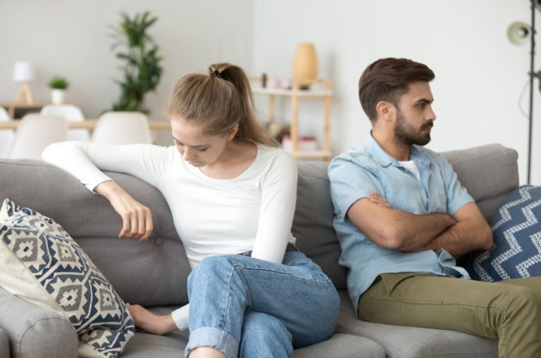 couple assis sur un canapé après une bagarre en s'ignorant