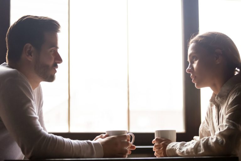 un homme et une femme sont assis à table et parlent