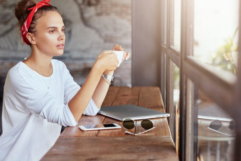 une belle fille rêveuse est assise à la table