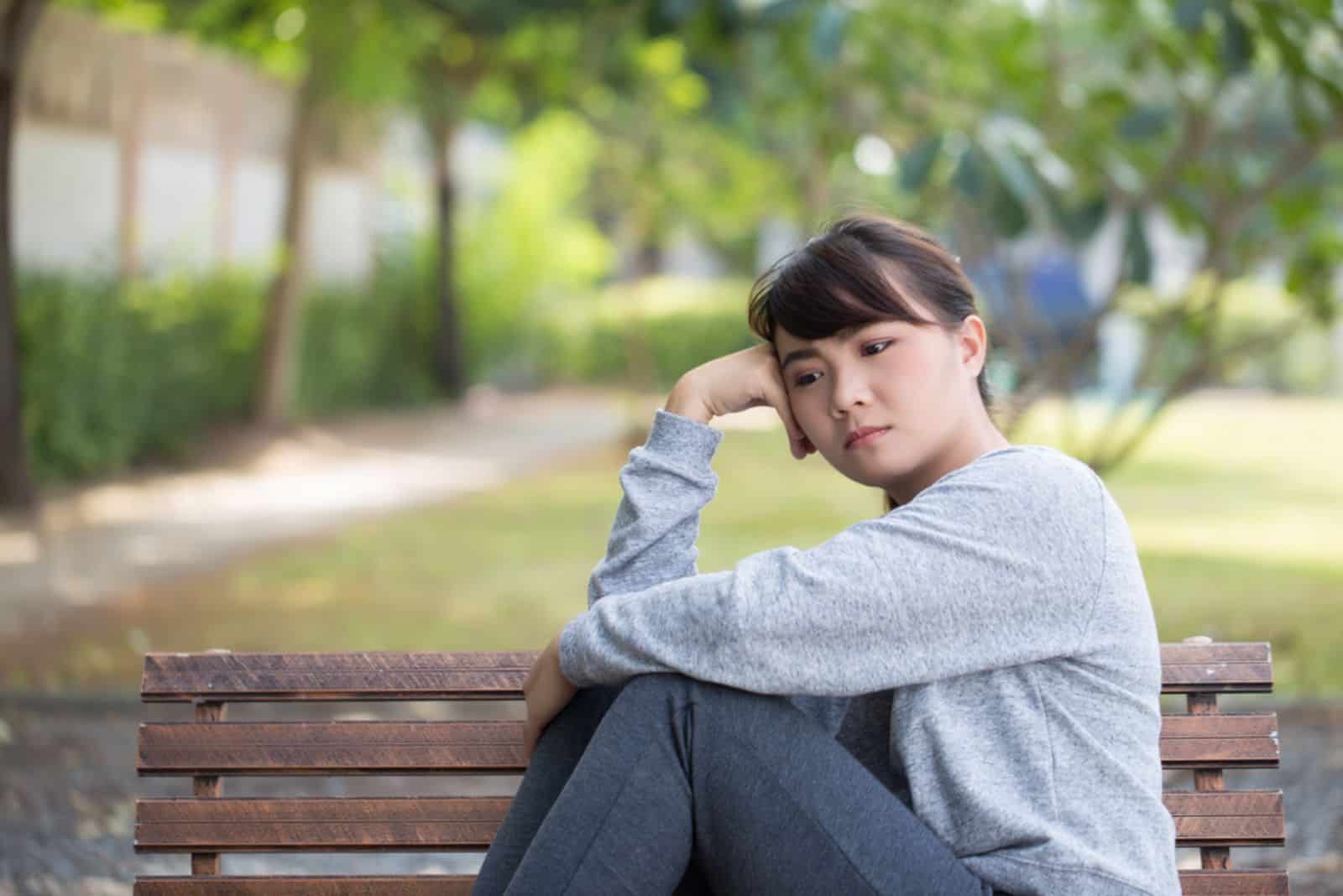 jeune femme triste assise sur le banc