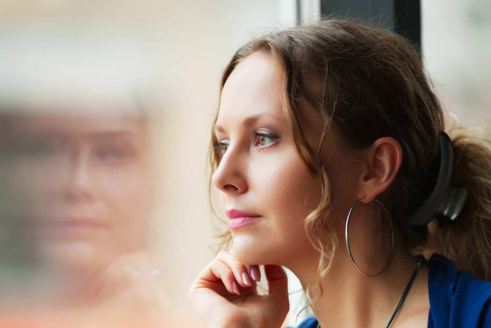 femme triste et contemplative regarde par la fenêtre