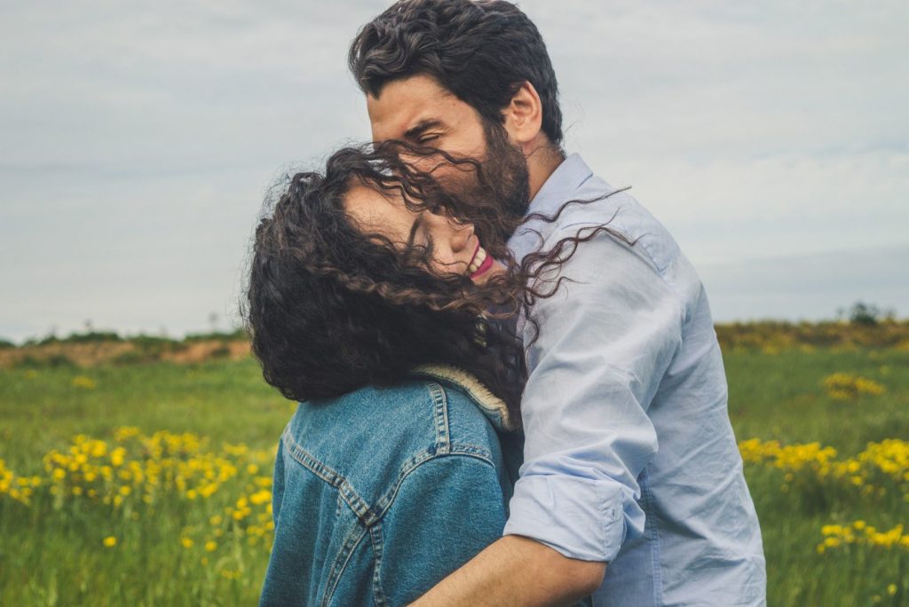 homme embrassant une femme heureuse dans le vent