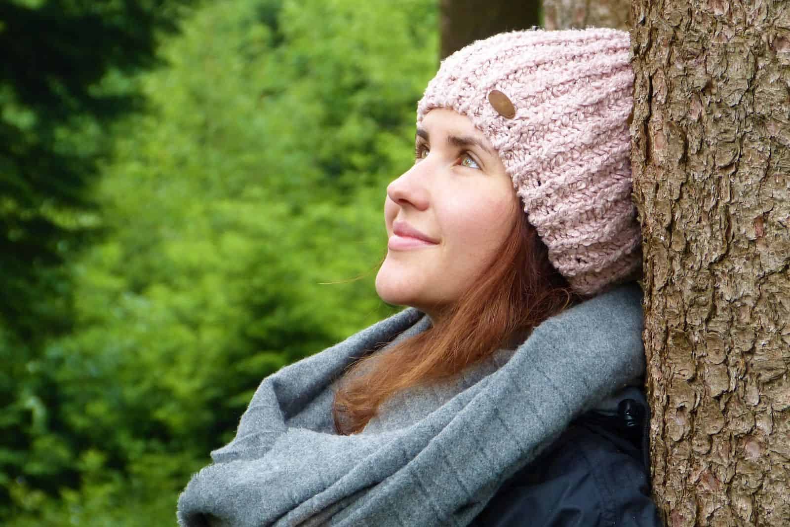 jeune femme souriante debout près de l'arbre