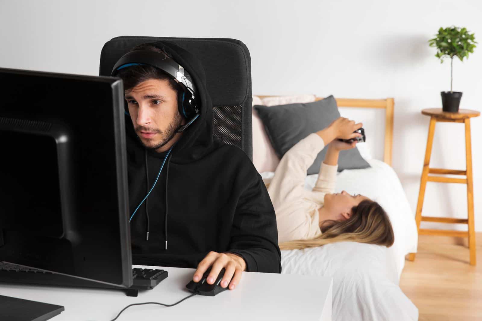 jeune homme jouant à des jeux sur ordinateur pendant que la femme est au téléphone