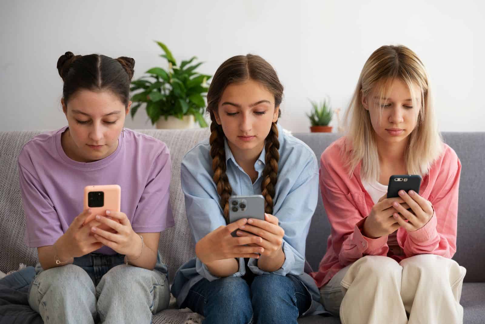trois filles assises sur le canapé et surfant sur internet