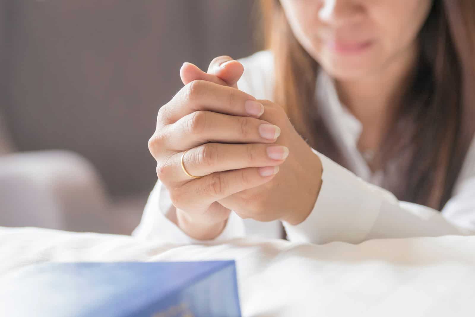 une femme allongée sur un lit prie