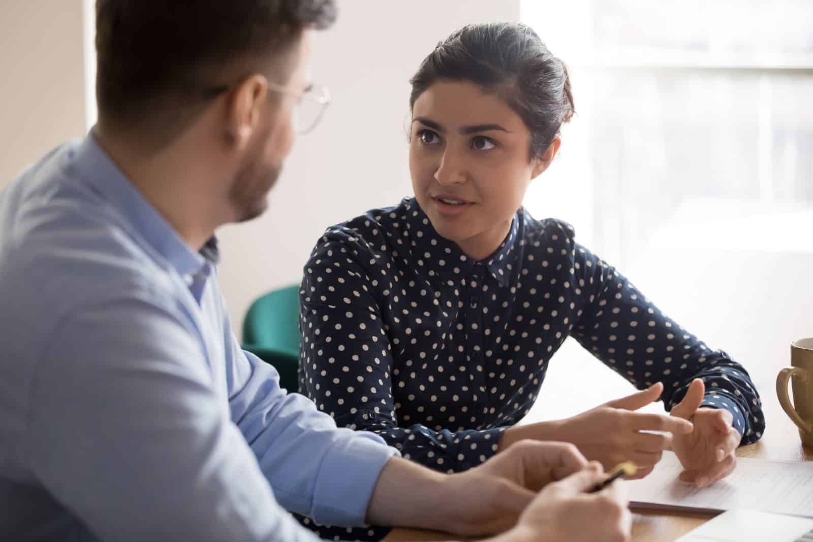 une femme aux cheveux attachés parle à un homme