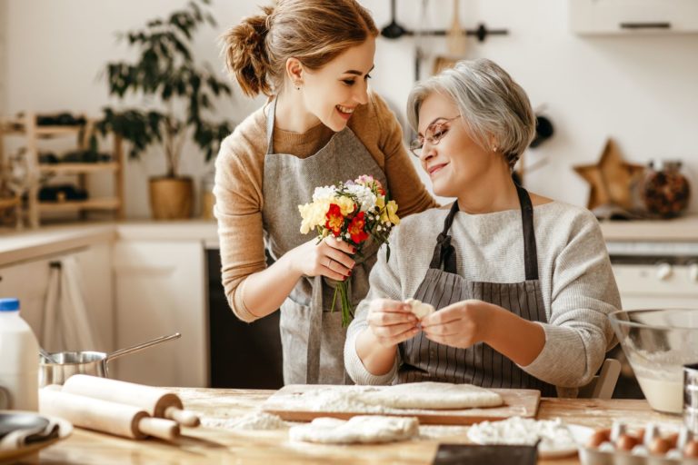 femme donne des fleurs à sa mère dans la cuisine pendant qu'elle cuisine
